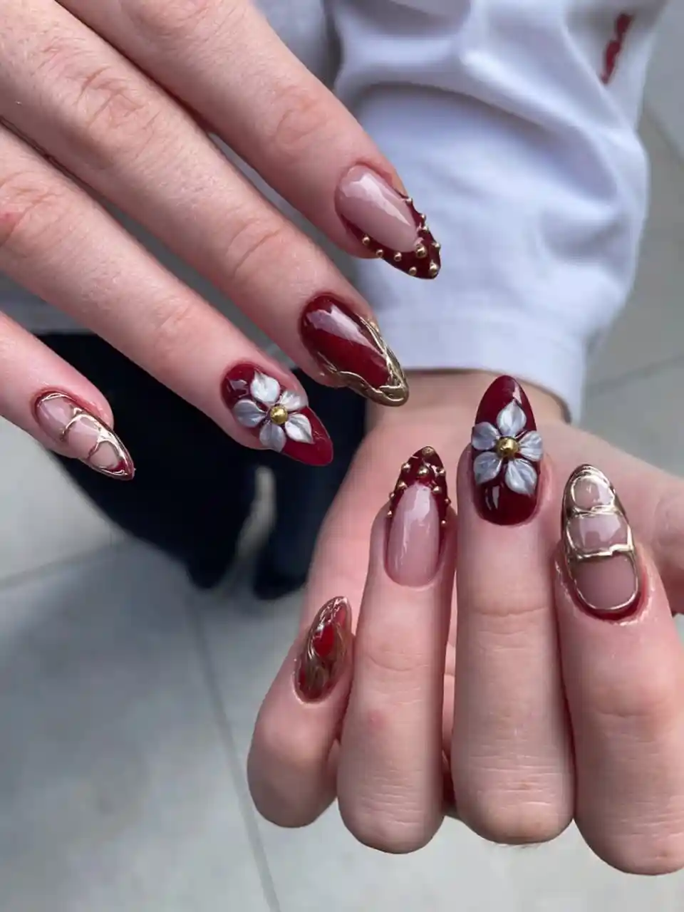 Burgundy and nude nails with 3D white flowers and gold outlines