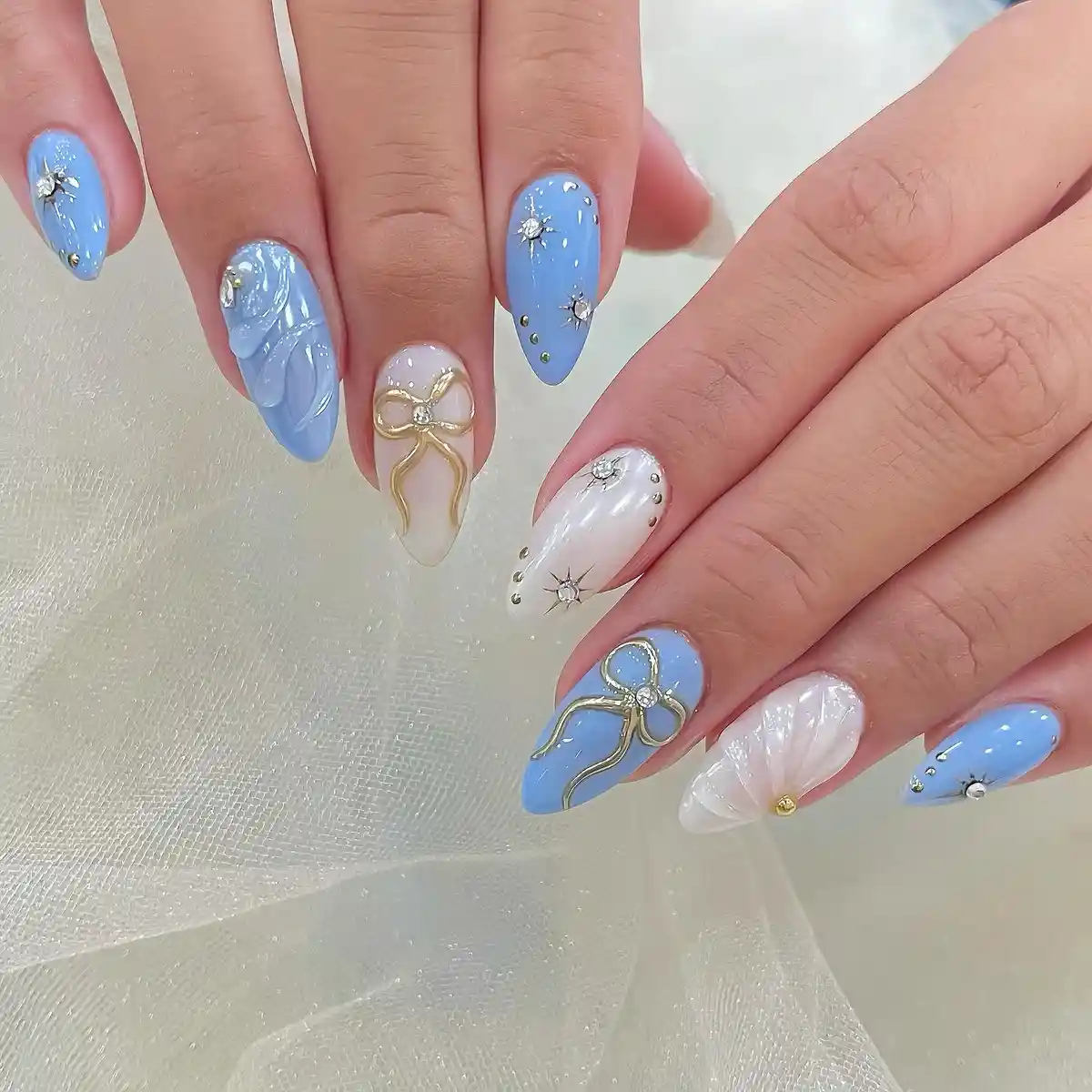 Light blue and white nails with 3D bows and stud accents