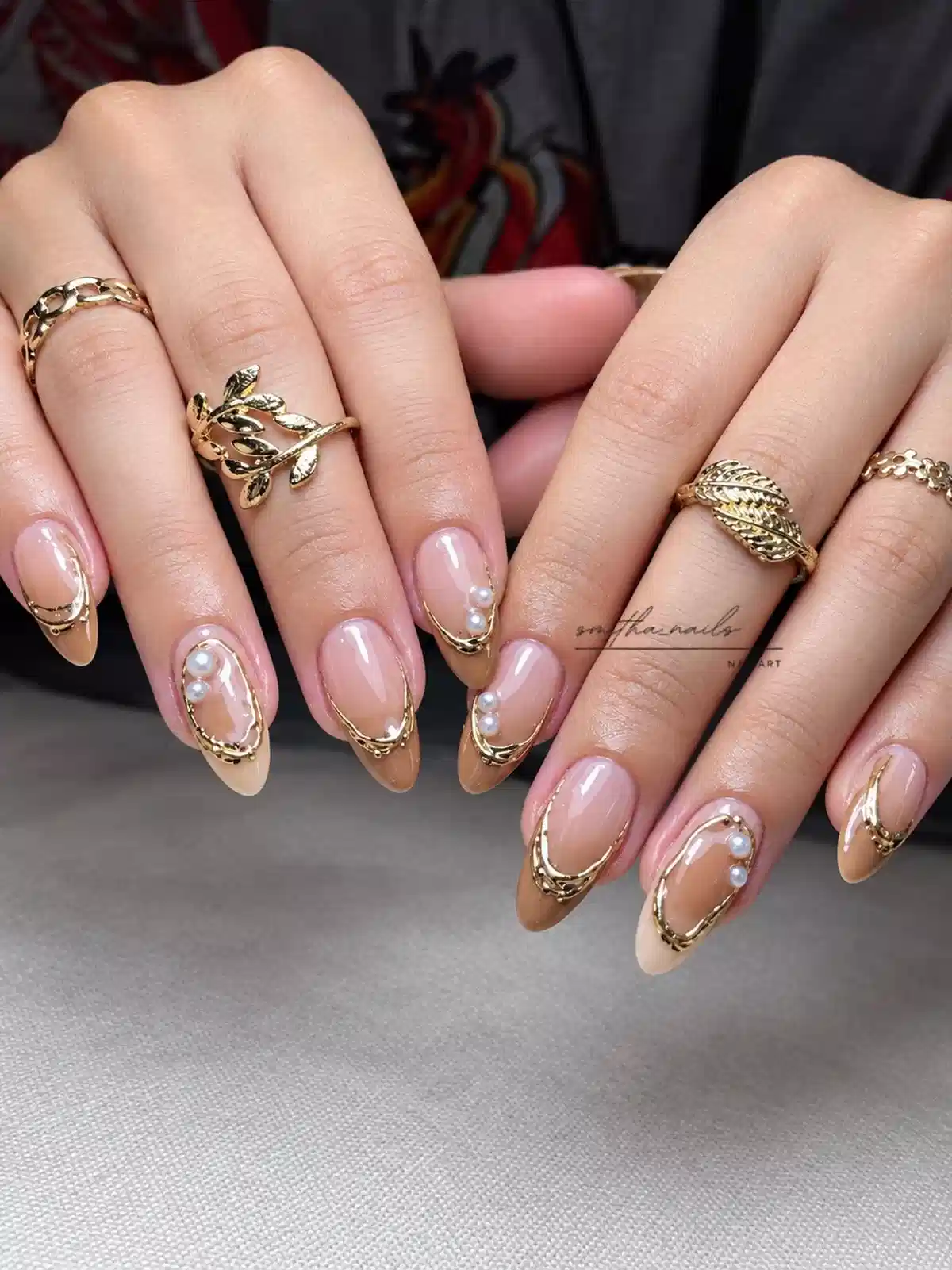 Nude-to-tan nails with gold frames and pearl accents
