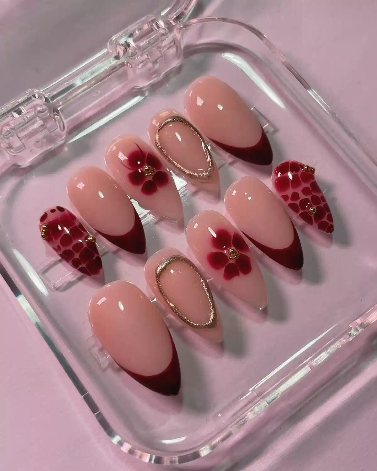 Nude pink and deep red French-tip set with floral and patterned accents