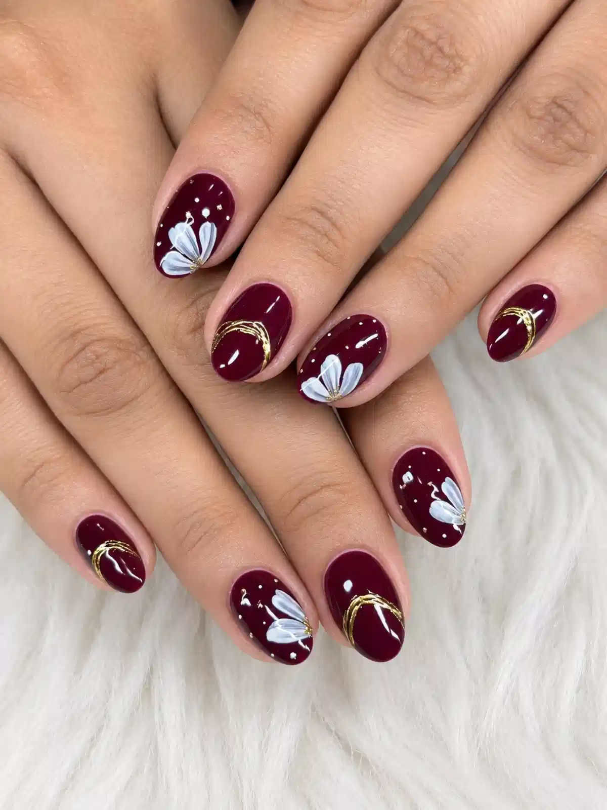Burgundy nails with white flowers and gold curves