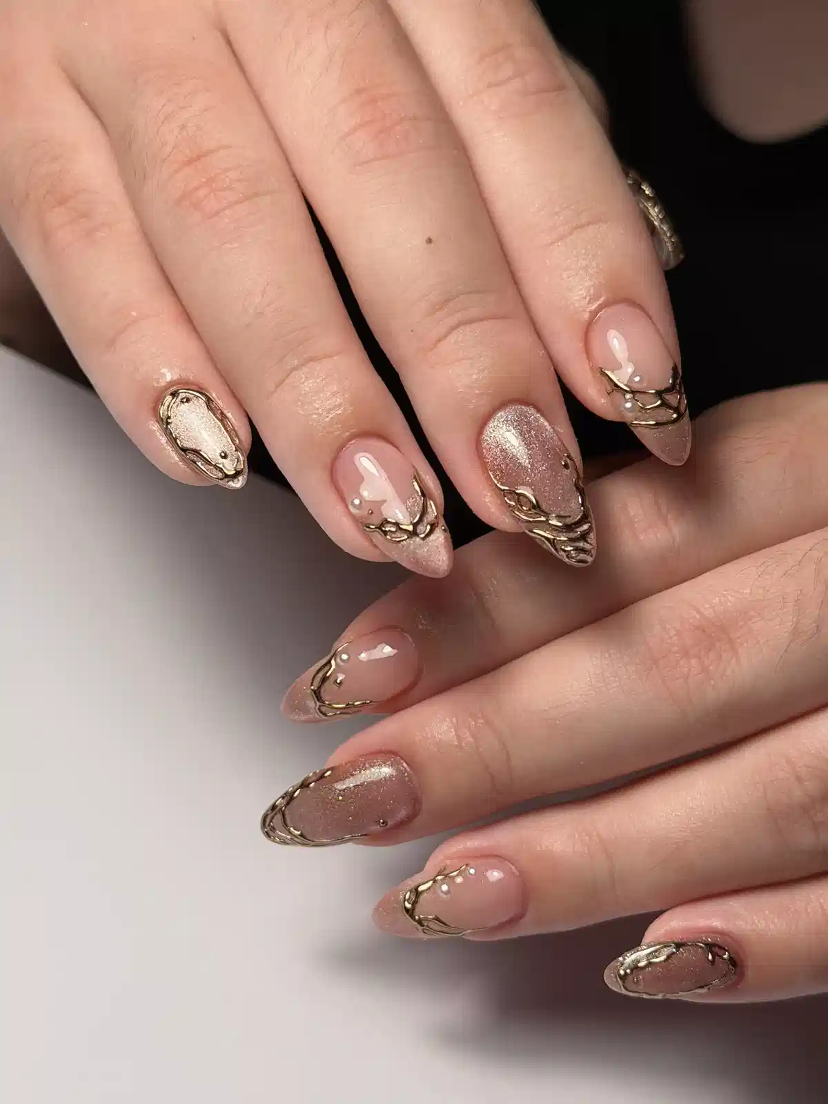 Nude and rose-gold glitter nails with raised gold chain accents