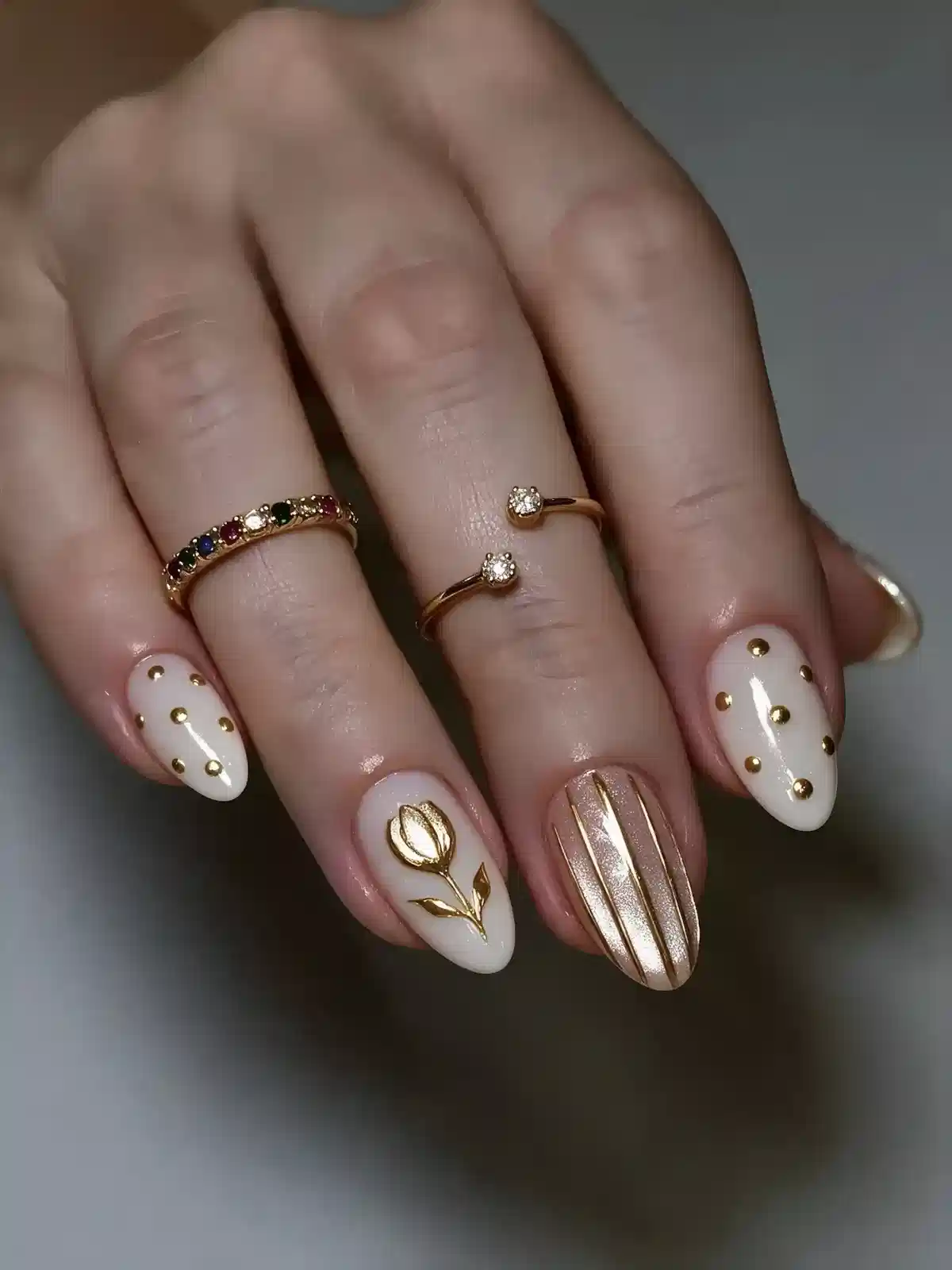 White nails with gold studs and raised gold floral accent