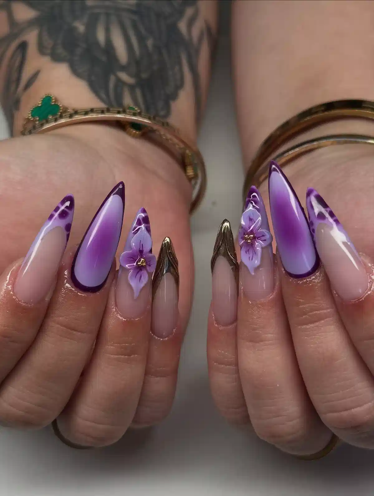 Purple ombre stiletto nails with gold V tips and floral accents