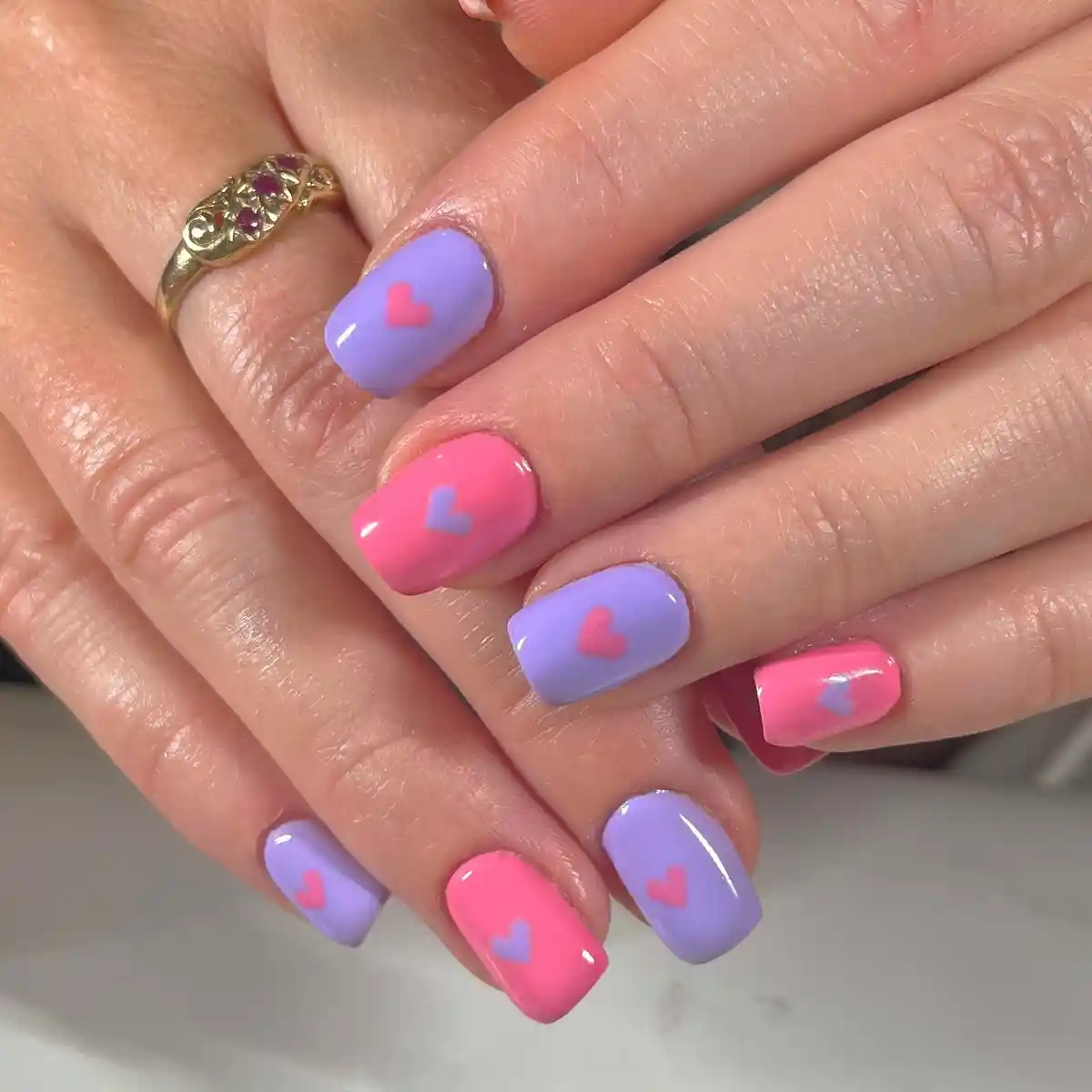 Alternating lavender and pink nails with small heart motifs