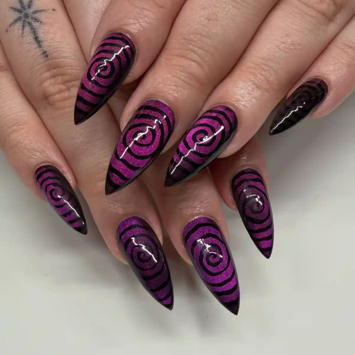 Magenta-purple stiletto nails with bold black spiral striping