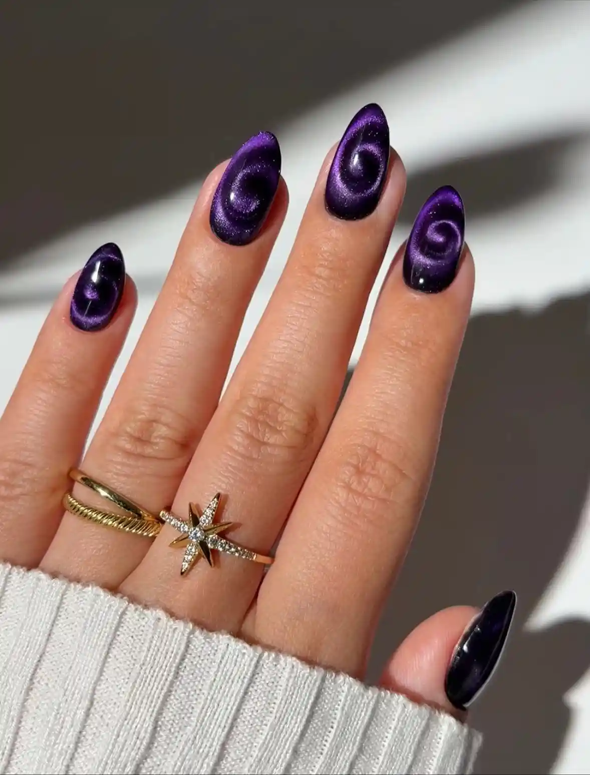 Dark purple cat-eye nails with spiral ring highlights