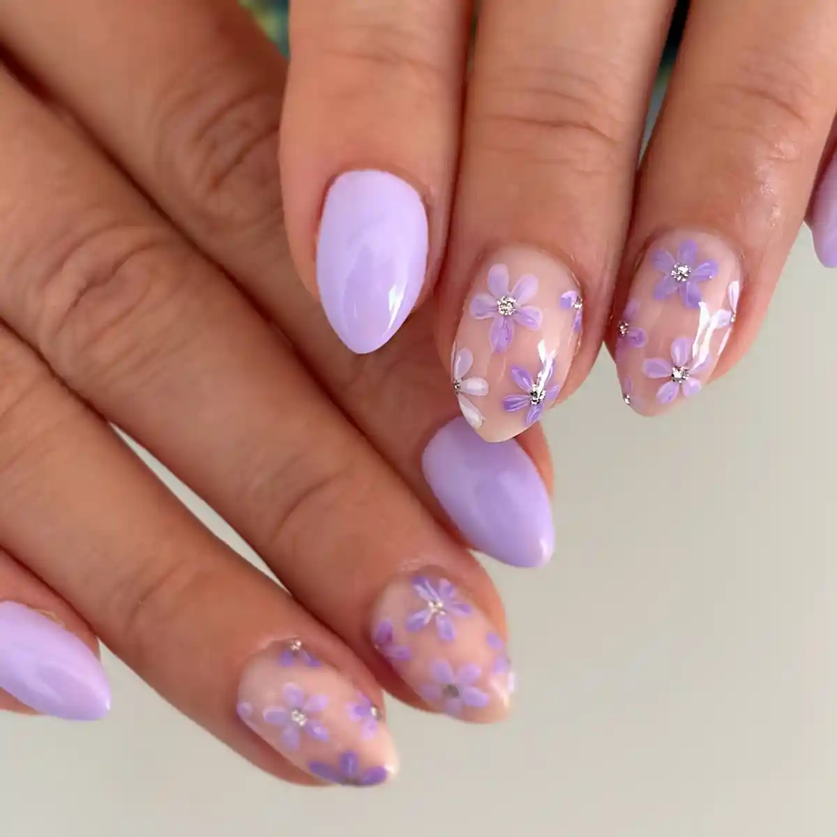 Light lavender nails with scattered mini flowers and rhinestone centers