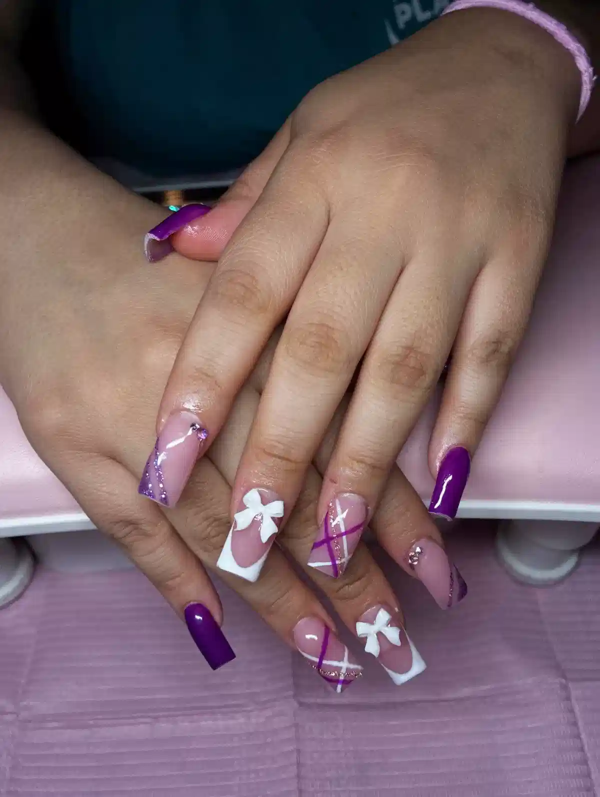 Deep purple and nude coffin nails with diagonal lines and white bows