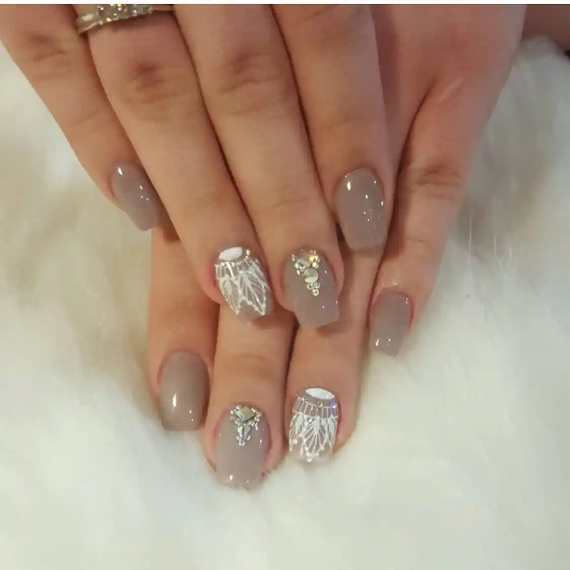 Glossy taupe nails with white line-art accents and rhinestones