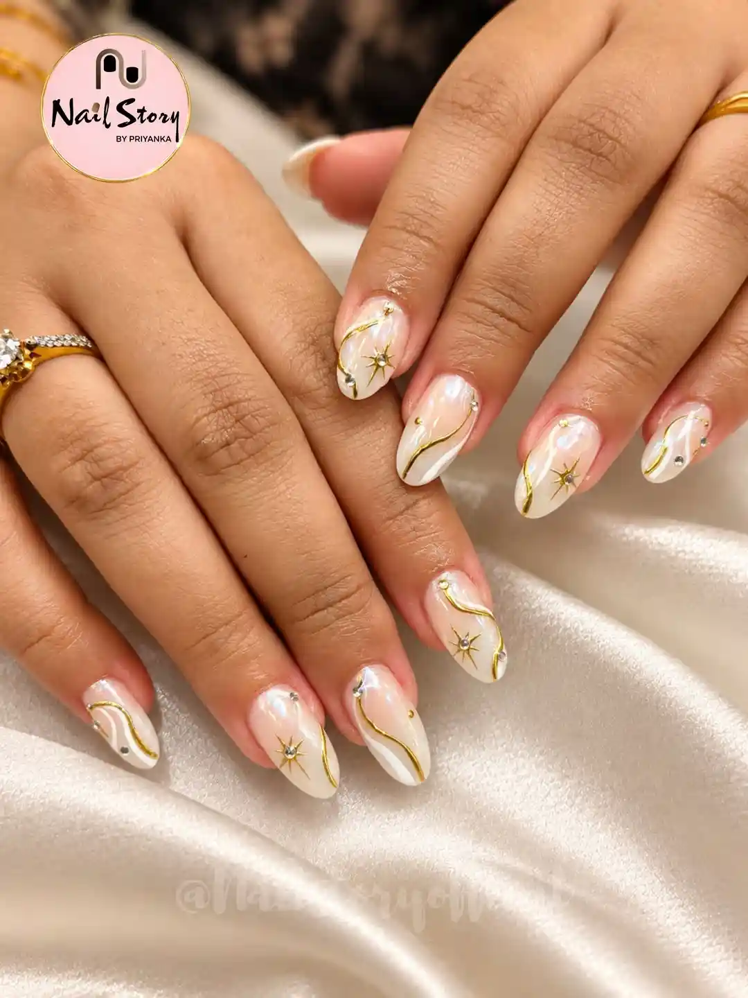 Pearl-sheen white nails with gold waves and starbursts